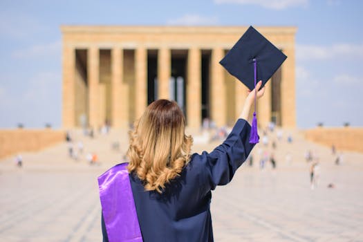 Graduate in cap and gown celebrating achievement at Anitkabir, Ankara.