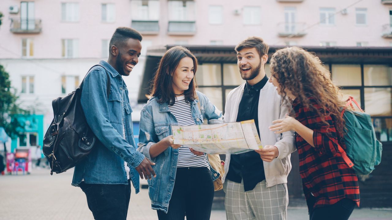 A group of friends happily exploring a city using a map. Perfect for travel and adventure themes.